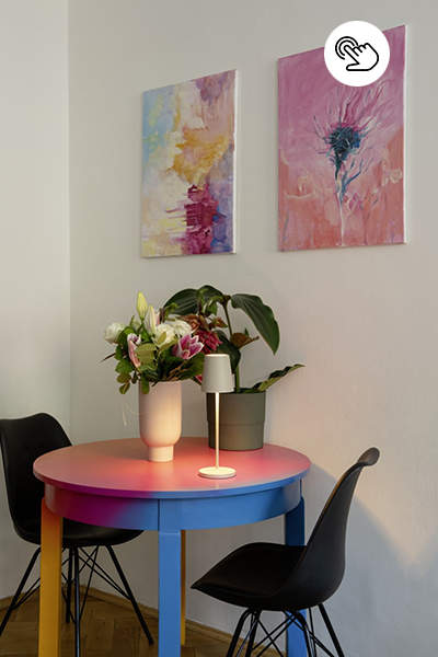 Bunter runder Tisch mit schlichter Akku-tischleuchte und Blumendeko