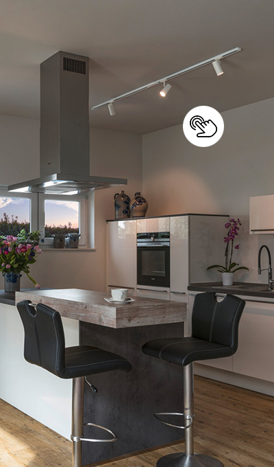 Helle Lichtschiene mit beweglichen Spots über einer Kücheninsel mit holzfarbenem Tresenbereich