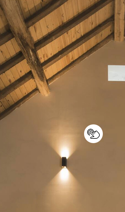 Hoher Raum mit sichtbaren Dachbalken und moderner, schwarzer Wandleuchte Hoher Raum mit sichtbaren Dachbalken und moderner, schwarzer Wandleuchte