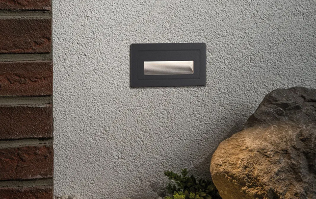 Wandeinbauleuchten entlang einer Steinmauer sorgen für Sicherheit auf Gartenwegen