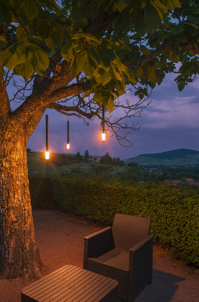 Leuchtstäbe an den Ästen sind eine kreative Lichtquelle für eine Loungeecke unter dem Baum