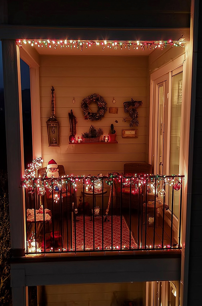 Lichterketten in den modernen Weihnachtsfarben Rot, Grün und Weiß am Geländer und Dach des Balkons