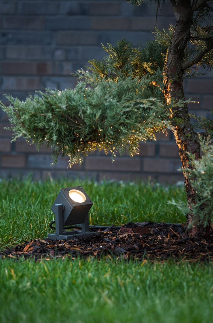 Minimalistischer schwarzer Gartenstrahler zur uneigennützigen Inszenierung eines Nadelbaums