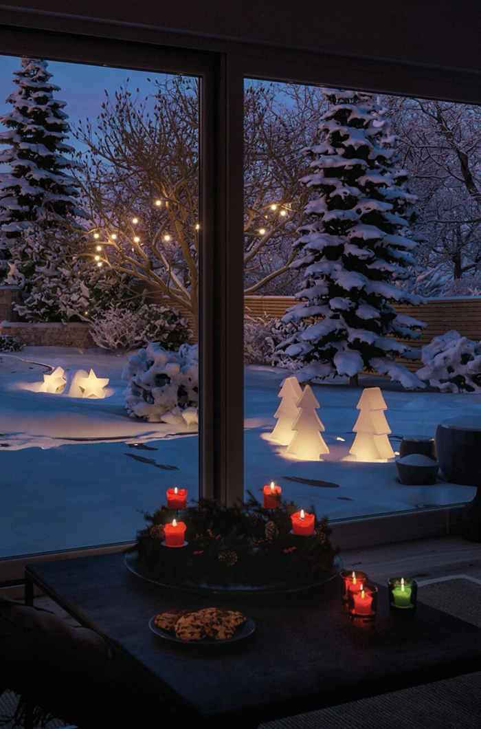Ein weihnachtlich mit LED-Figuren und Lichterketten erhellter schneebedeckter Garten ist auch vom Wohnzimmer aus ein herrlicher Anblick