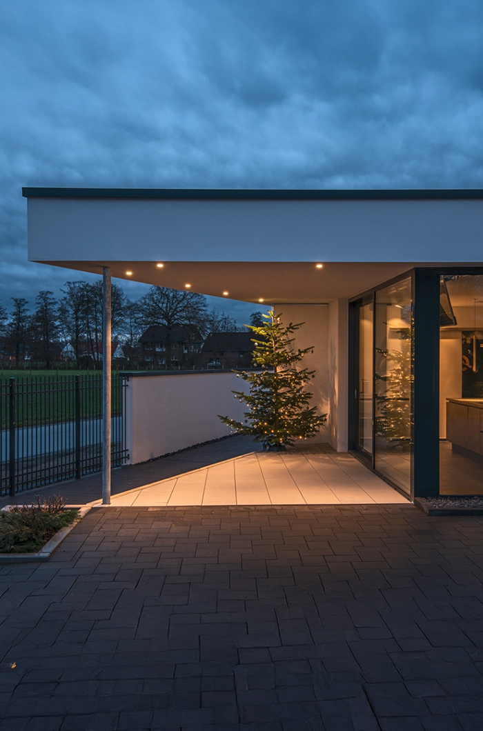 Überdachter Außenbereich mit einem beleuchteten Weihnachtsbaum und funktionellen Deckeneinbaustrahlern für eine minimalistische Lichtdeko